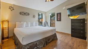 Une chambre à coucher avec un grand lit, un ventilateur de plafond, une télévision et une commode.