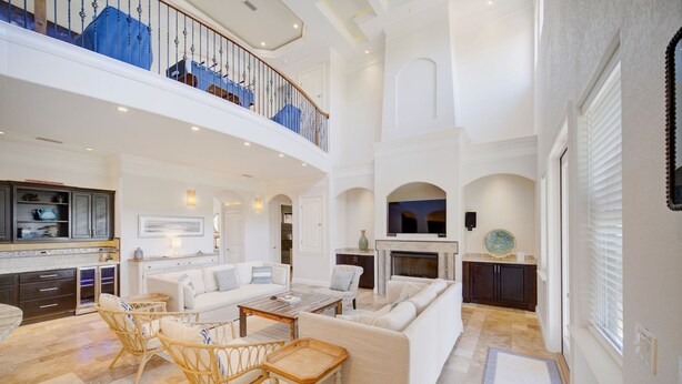 A spacious living area with a high ceiling, a fireplace, and a balcony.