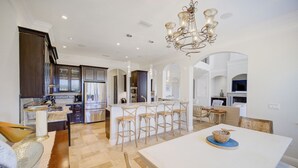 A spacious kitchen with dark wood cabinets, a central island with bar stools, and a dining area with a white table and chairs.