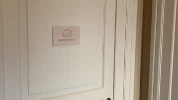 Une porte blanche avec une plaque portant le nom « MADREPERLA » et une poignée de porte en laiton.