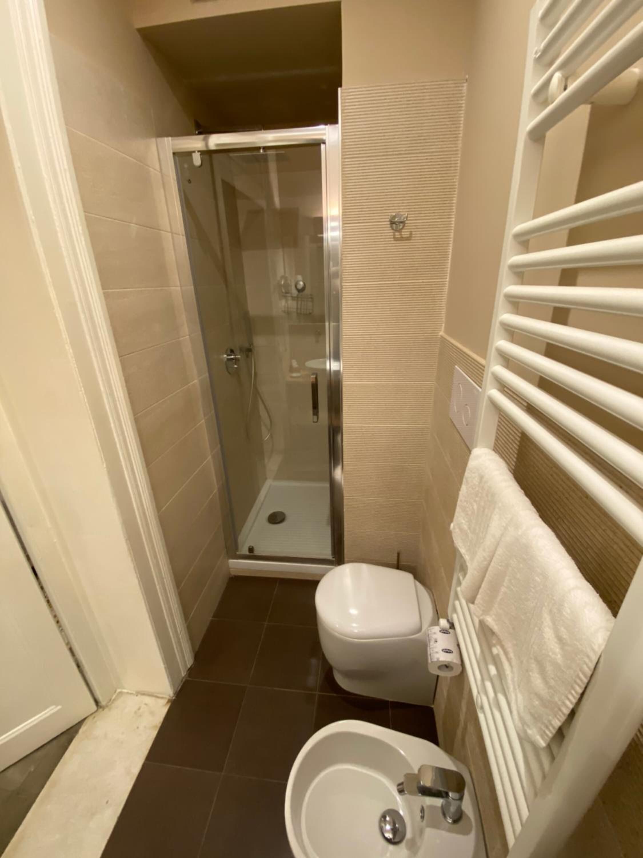 A compact bathroom with a glass-enclosed shower, a toilet, and a sink.