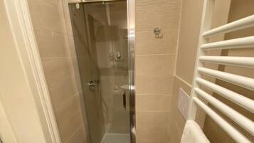 A compact bathroom with a glass-enclosed shower, a toilet, and a sink.