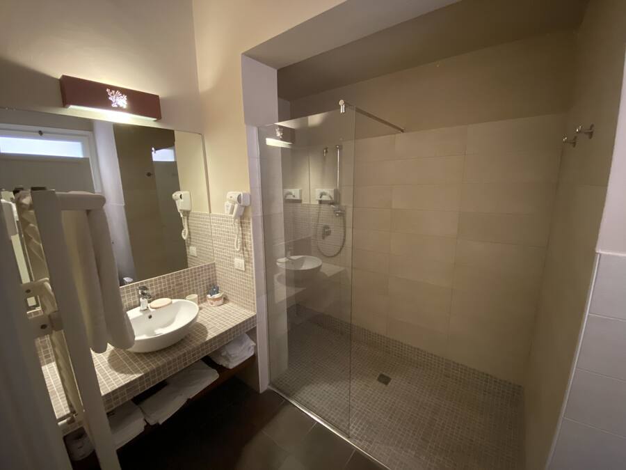 A modern bathroom with a glass-enclosed shower, a sink with a mirror, and a towel rack.