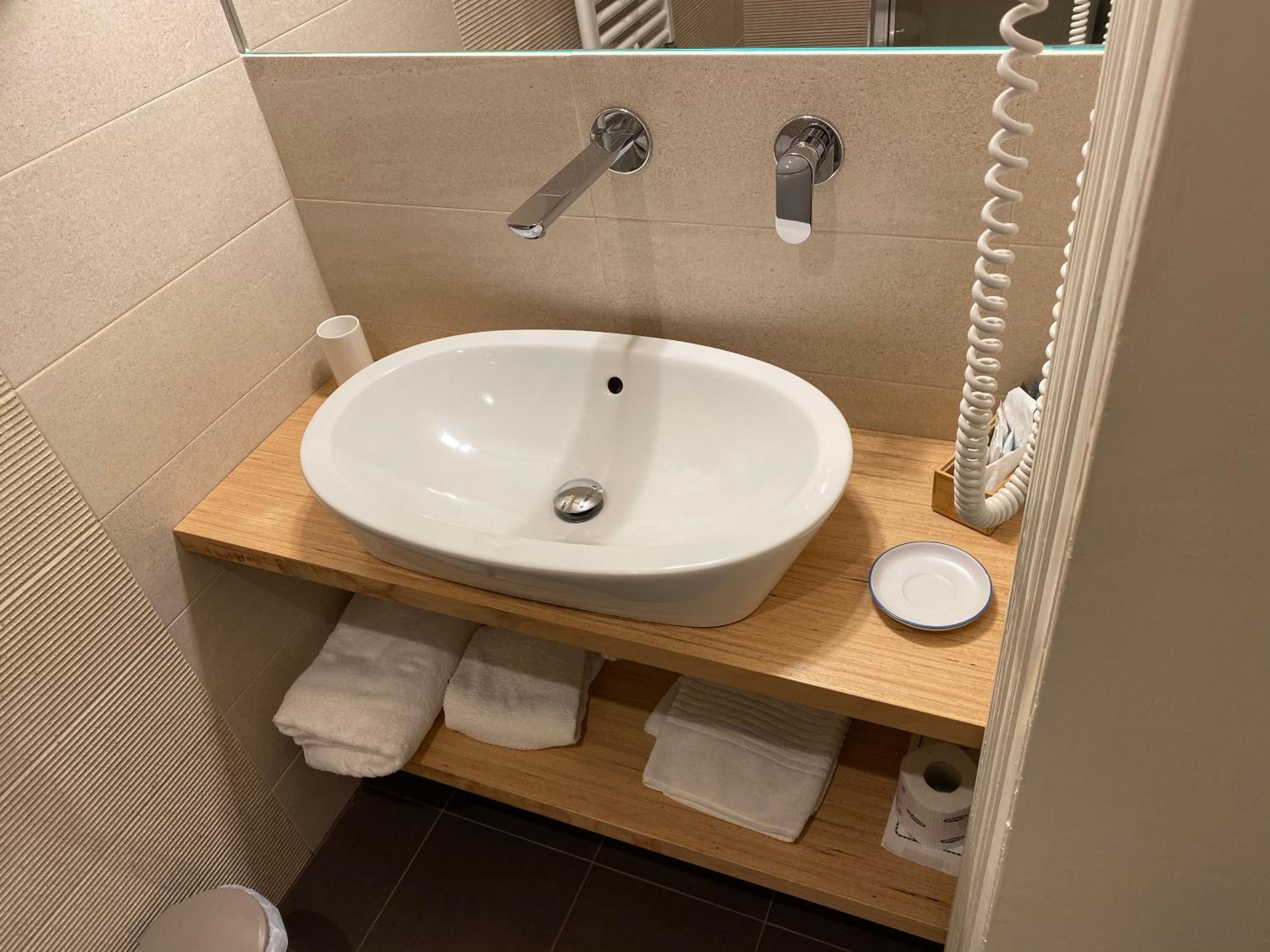 A bathroom with a white sink, wooden vanity, and a towel rack.