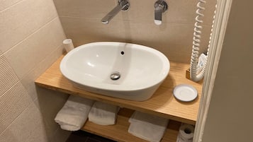 Une salle de bain avec un lavabo blanc, un meuble-lavabo en bois et un porte-serviettes.