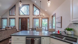 A spacious kitchen with a large island, multiple windows, and a dining area. - Hot Tub • Game Loft • Walk to Local Attractions • Sleeps 10 (Broken Bow)
