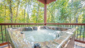 A hot tub on a wooden deck with a metal railing, surrounded by trees. - Hot Tub • Game Loft • Walk to Local Attractions • Sleeps 10 (Broken Bow)