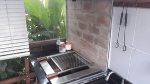 Een keuken met een metalen grillplaat, een spoelbak en een raam met zonwering.