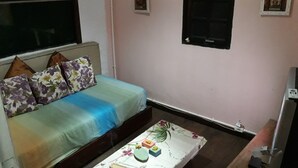 Een kleine, gezellige kamer met een enkel bed, een nachtkastje en een raam.