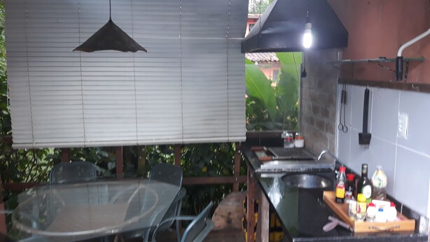 Een keuken met een groot fornuis, een hanglamp en een raam met jaloezieën.
