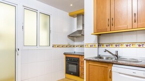 Una cucina compatta con mobili bianchi, forno integrato, lavello e lavastoviglie.