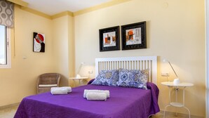 Camera d'albergo con un letto grande, due comodini, una poltrona e opere d'arte alle pareti.