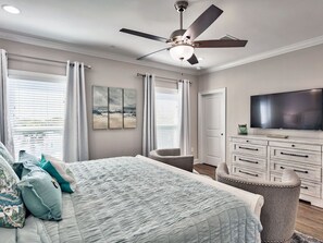 A bedroom with a bed, a ceiling fan, a TV, a dresser, and a window with curtains. - Luxury Townhome, Golf Cart, Short Walk to Beach, Pool, Sleeps 13 (Miramar Beach)