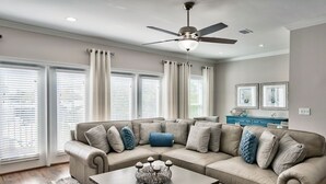 Un soggiorno con un divano angolare beige, un tavolino in legno e una ventola a soffitto.