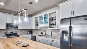 Una cucina moderna con mobili bianchi, elettrodomestici in acciaio inossidabile e un'isola in legno.
