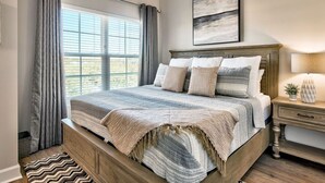 Una camera da letto con un letto grande, un comodino, una finestra con tende e una ventola a soffitto.