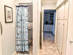 A hallway with a light blue curtain featuring nautical designs, leading to a kitchen area with white cabinets and a tiled floor. - 1 Block to Beach, Tiki Bar, Spacious Fenced Backyard, Splash Pool (Destin)