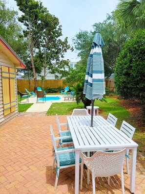 A backyard with a pool, patio furniture, and a covered table and chairs. - 1 Block to Beach, Tiki Bar, Spacious Fenced Backyard, Splash Pool (Destin)