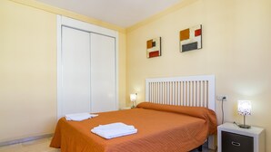 Une chambre d’hôtel avec un lit, une table de chevet, une lampe et deux tableaux abstraits accrochés au mur.