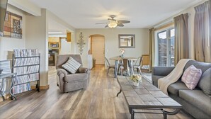 A living room with a sofa, armchair, coffee table, and a dining area with a table and chairs. - Charming 2 Bedroom w/ Private Hot Tub and Mountain views! (Estes Park)