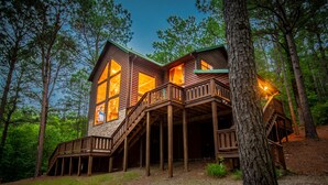 A cabin with a wooden exterior, multiple windows, and a deck area.