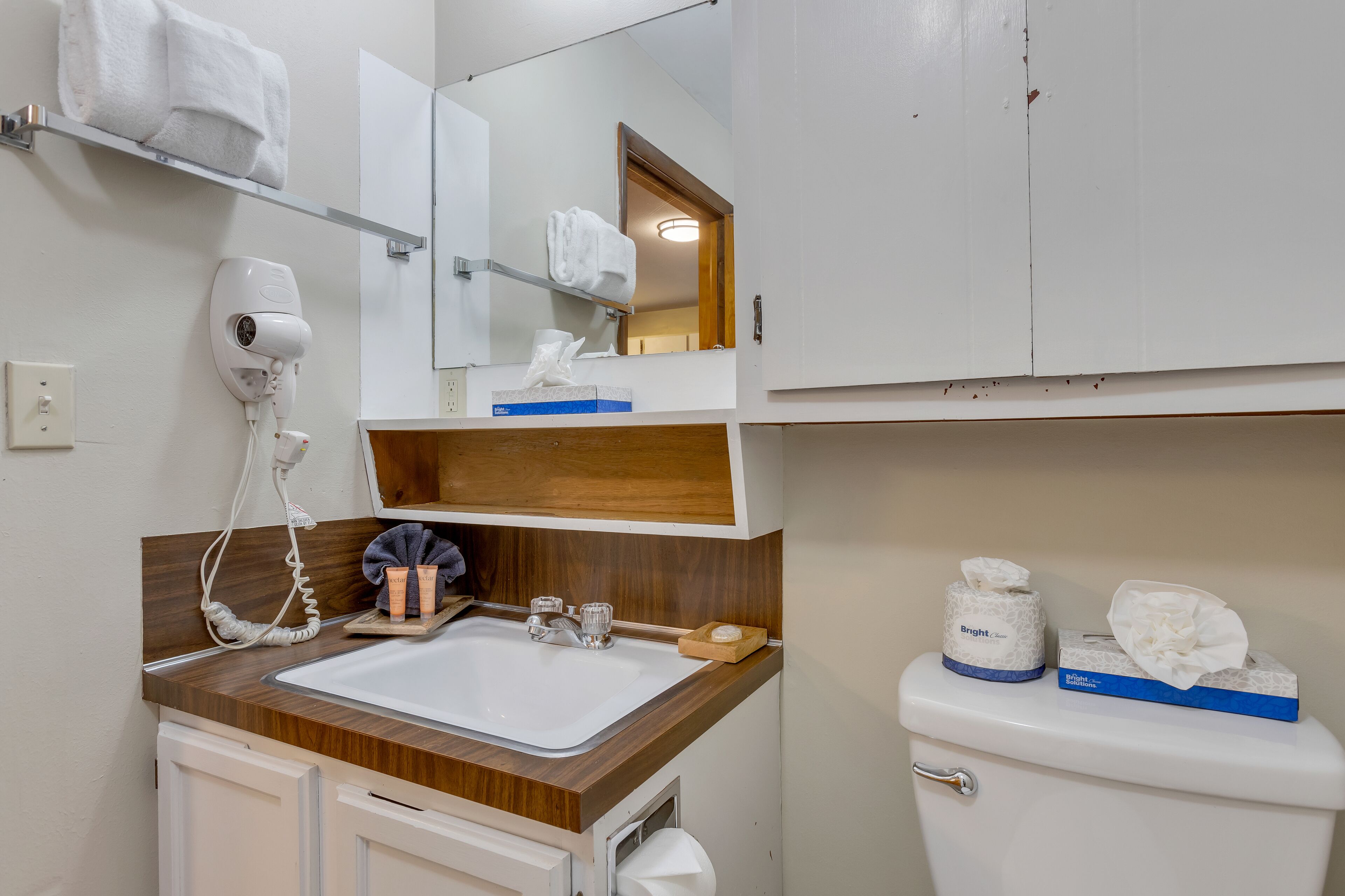 A bathroom with a sink, mirror, towel rack, and toilet.