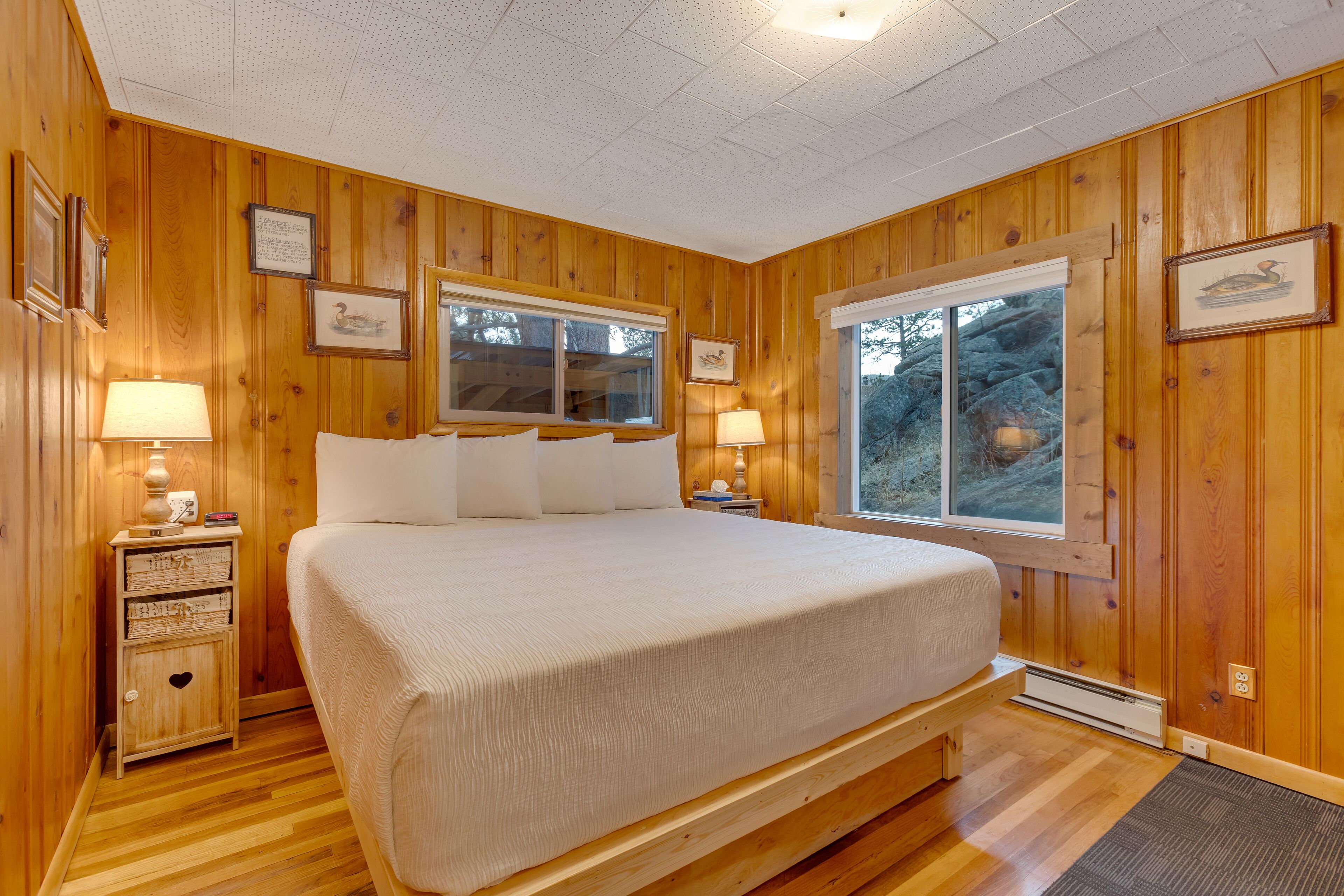 Une chambre à coucher aux murs lambrés, avec un grand lit, deux tables de chevet et des tableaux encadrés.