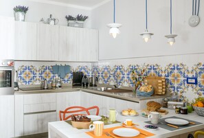 Une cuisine moderne avec des meubles blancs, un pare-feu en carrelage et divers appareils de cuisine.