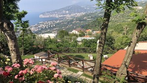 Ein Garten mit einer Holzpergola und Blick auf eine Küstenstadt.