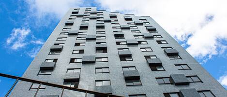 A tall building with a grid of windows and balconies, viewed from a low angle.