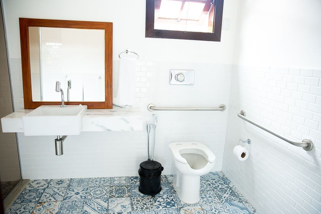 A bathroom with a sink, toilet, and handrail.