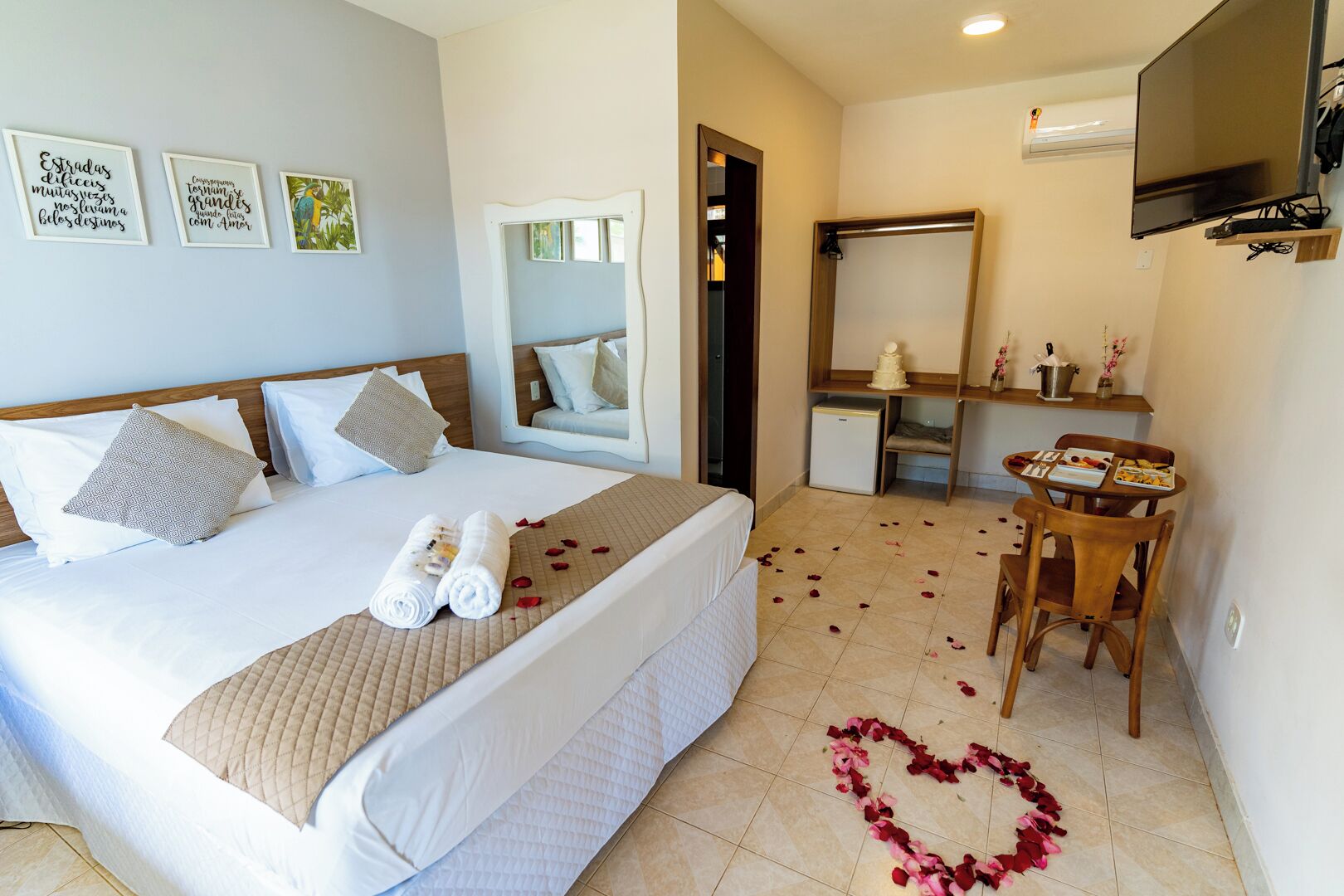 A hotel room with a bed, a desk, a mirror, and a television.