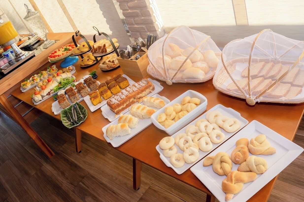 A buffet table with various food items and bread baskets.