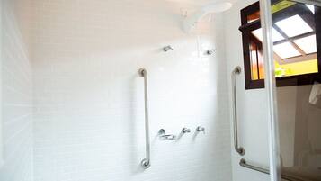Ein Badezimmer mit weißen Fliesen, einer Duschkabine aus Glas und einem Fenster mit Blick.