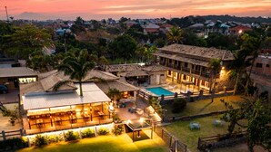 Un resort con piscina, mobiliario exterior y una zona de patio bien iluminada.