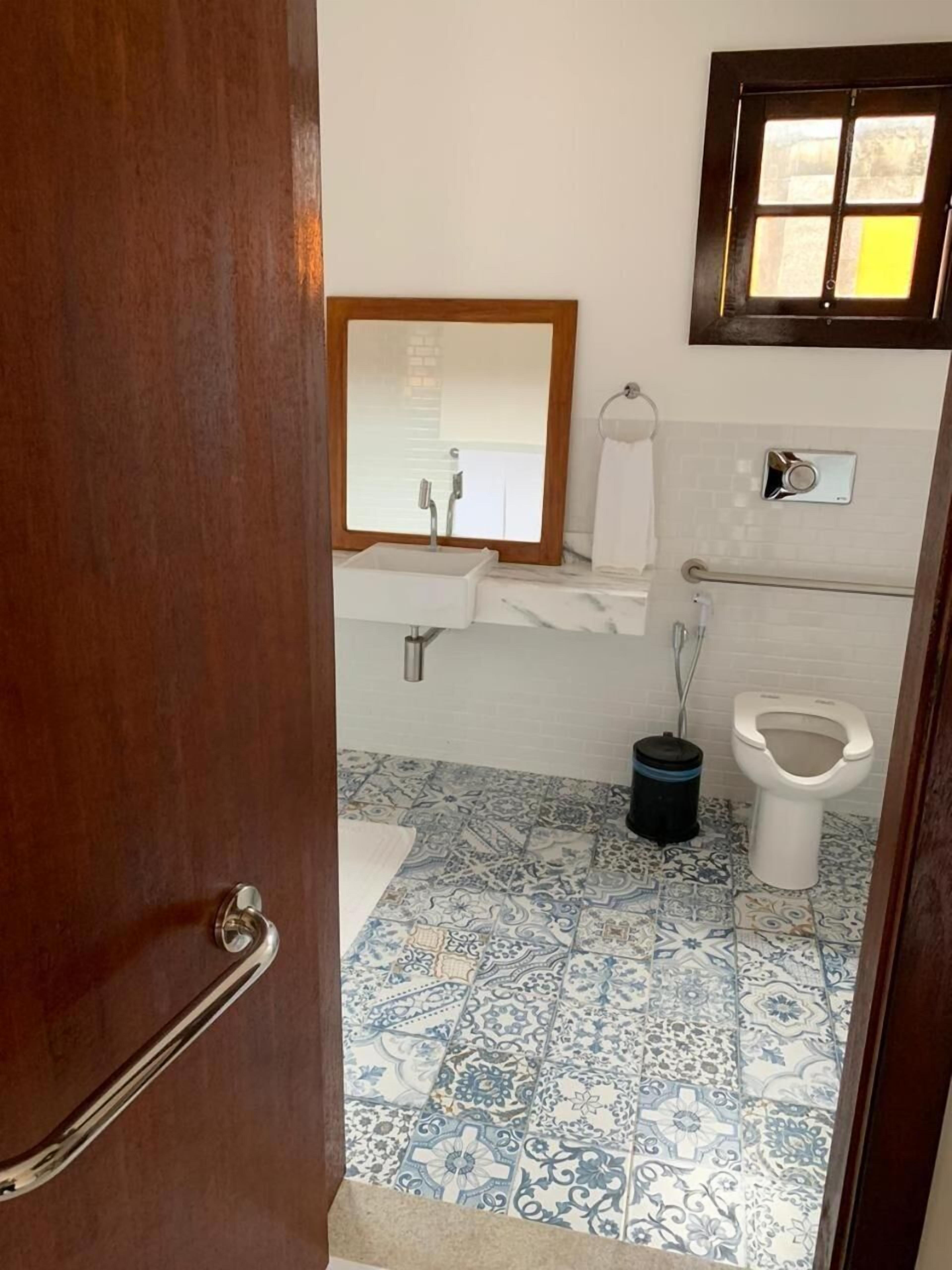 A bathroom with a white sink, a mirror, a toilet, and patterned blue and white tiles.