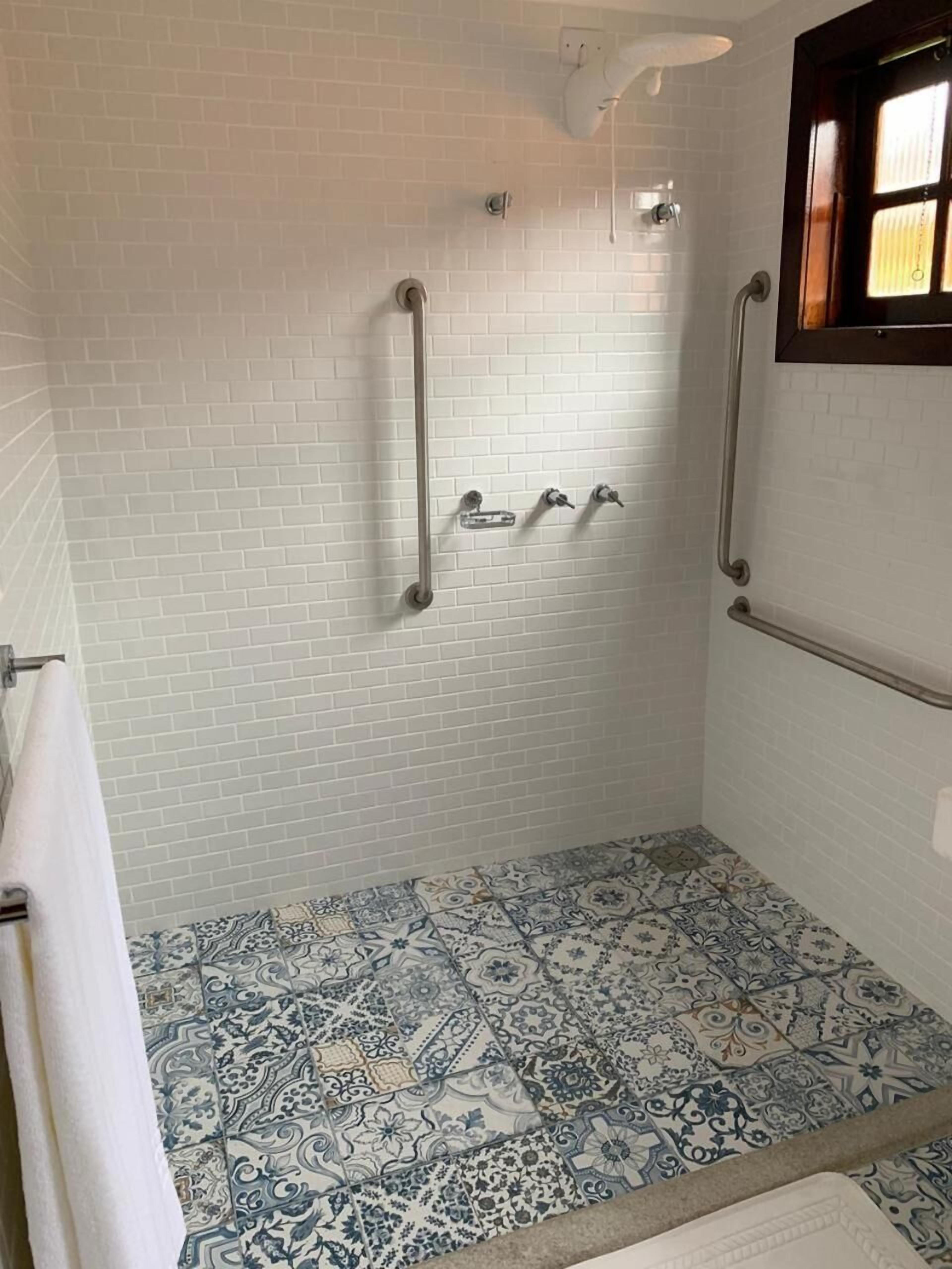 Een badkamer met witte betegelde wanden, een patroon vloer en een raam met zonwering.