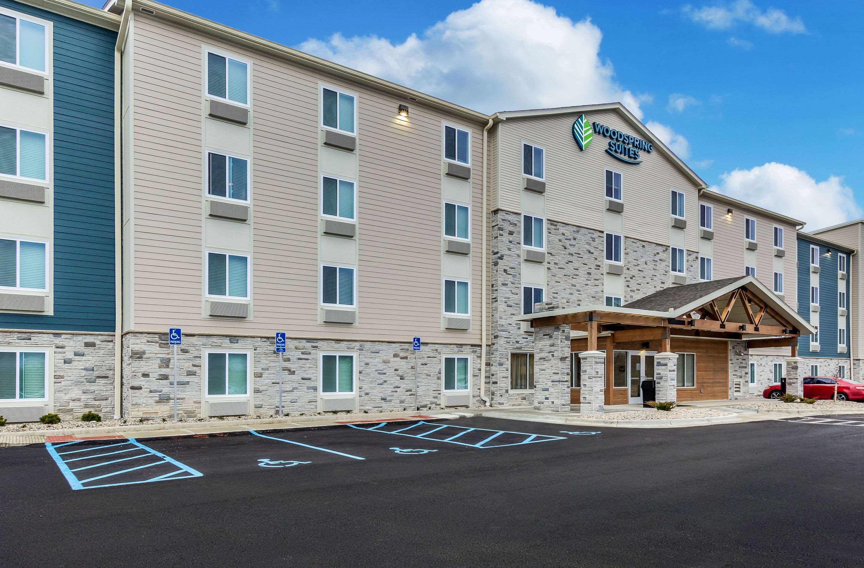 A multi-story hotel with a stone facade, a covered entrance, and a parking lot with handicapped accessibility.