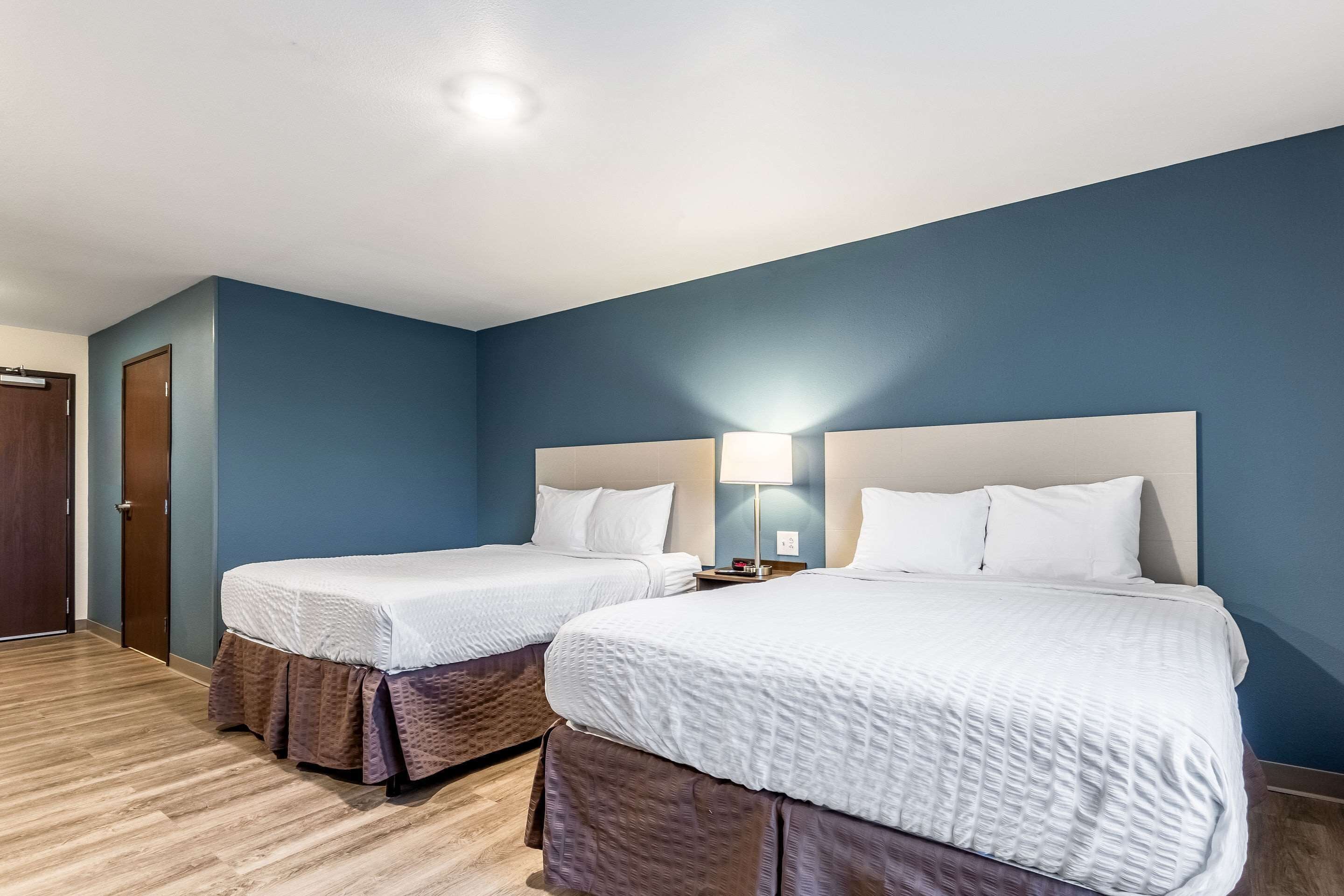 Une chambre d’hôtel avec deux lits, un plancher en bois et un mur bleu.