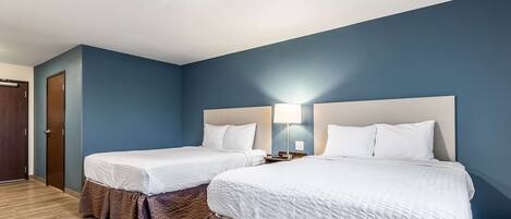 Habitación de hotel con dos camas, piso de madera y pared azul.
