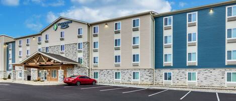 A multi-story hotel with a stone facade, a red car parked in front, and a clear blue sky.