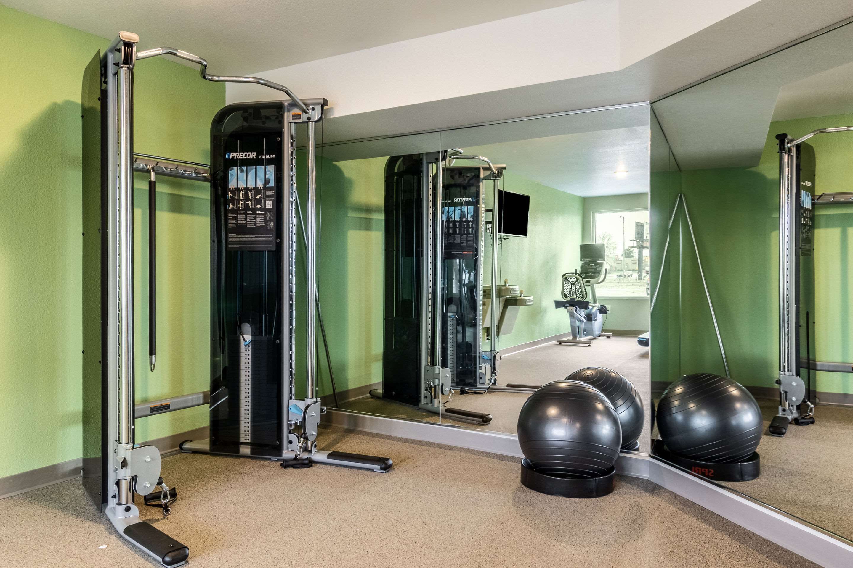 A gym with exercise equipment, a mirror, and exercise balls.