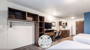 A hotel room with a bed, a desk, a television, and a kitchenette. - WoodSpring Suites Indianapolis Castleton (Indianapolis)