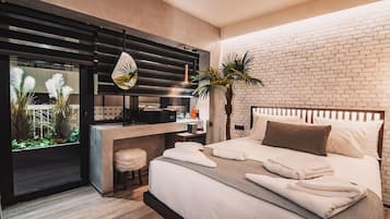 Una habitación de hotel moderna con una cama grande, un escritorio y vistas a un muro de ladrillos.