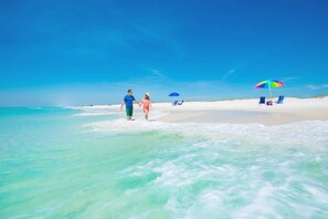 Una playa con agua turquesa cristalina, una orilla arenosa y algunas sombrillas.