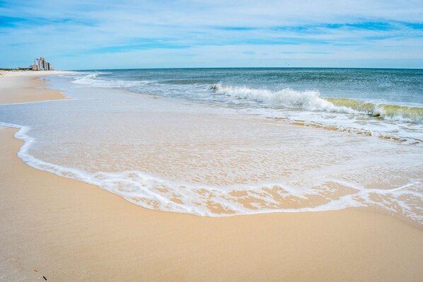 A beach with a sandy shore and ocean waves.