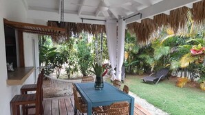 Un portico coperto con tavolo e sedie in legno, immerso nel verde e con un'amaca.