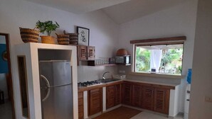 Una cucina con frigorifero, piano cottura, pensili e una finestra vista verde.