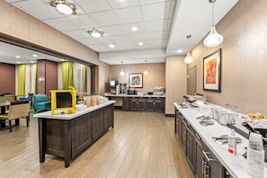 A modern hotel lobby with a reception desk, seating area, and a buffet counter.