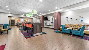 Eine moderne Hotelhalle mit Empfangsbereich, Sitzgelegenheiten und einer Wand mit Dekoration.